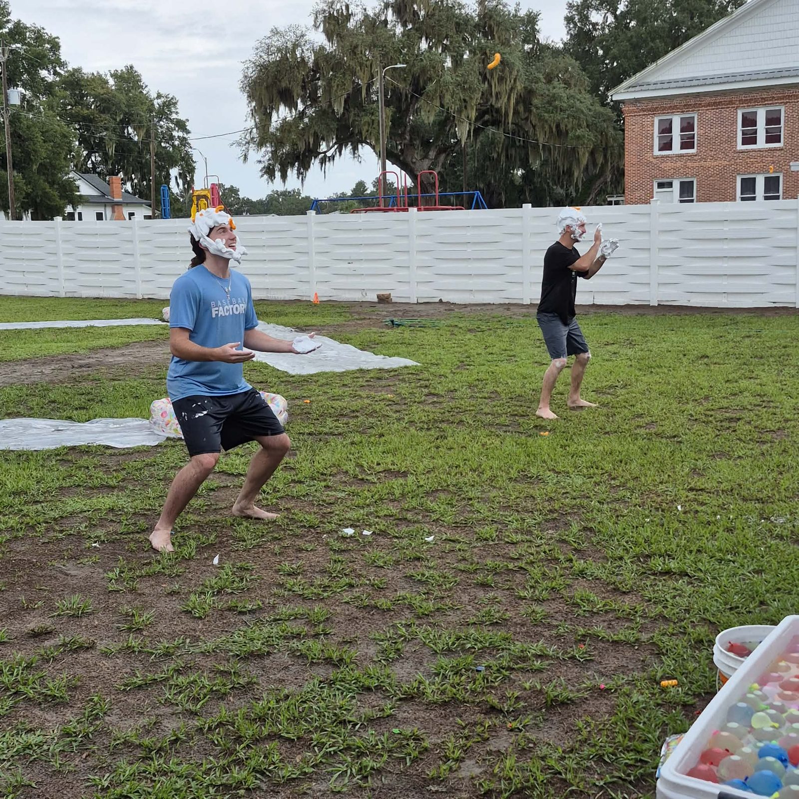 Two students with shaving cream and cheese puffs on their heads playing a fun events game outdoors