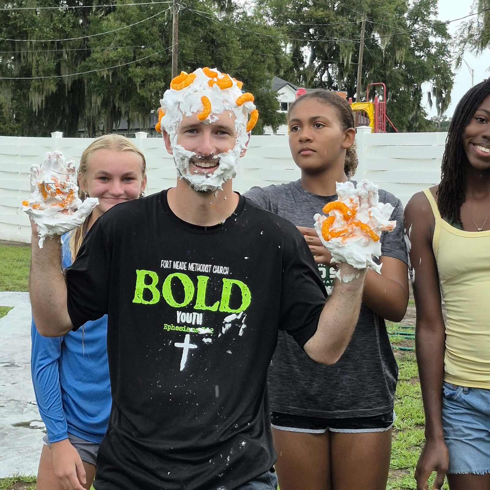 A student wearing a Bold Youth shirt covered in shaving cream and cheese puffs during a fun events game