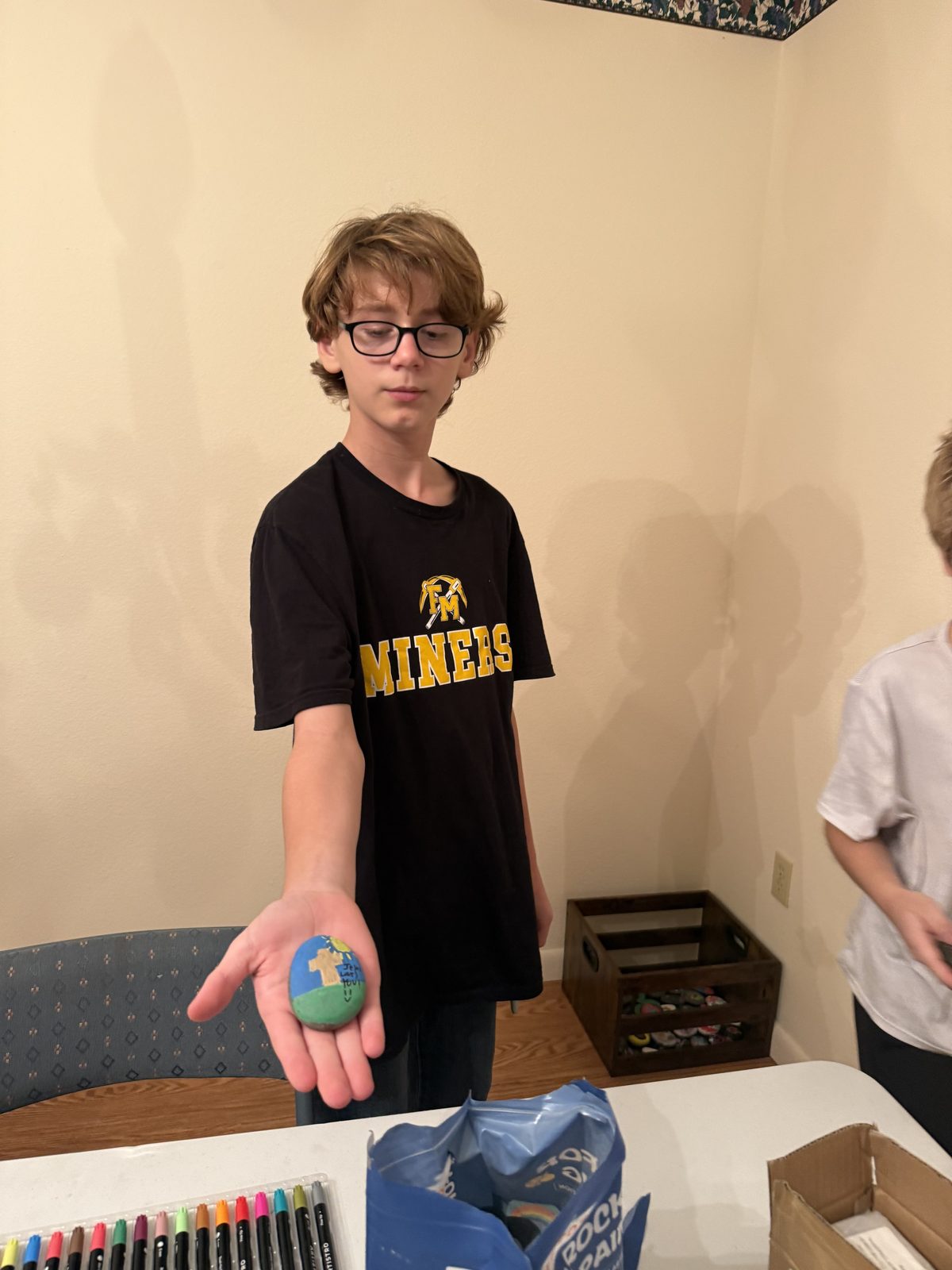 A student holding a hand-painted rock during a fun events craft night