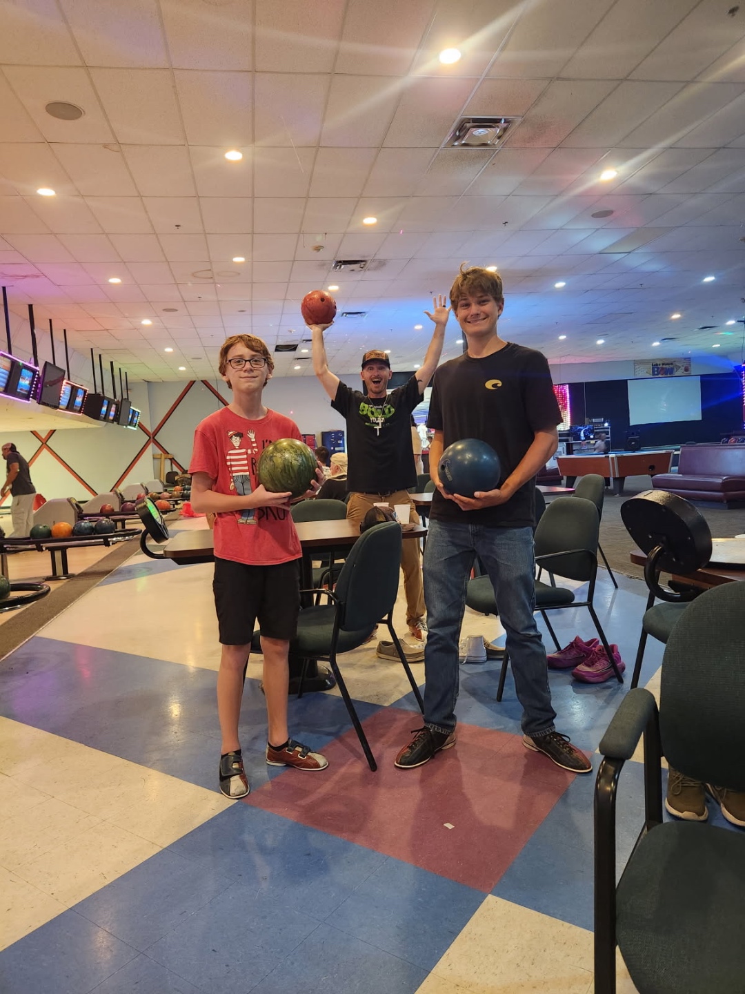 Students holding bowling balls and celebrating a strike on game night